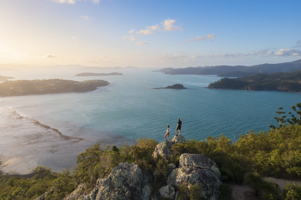 Couple enjoying the view on top mountain overlooking Whitsundays ocean